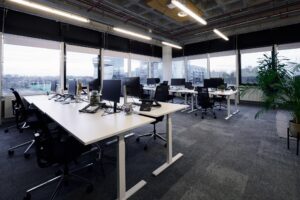 Moderne open kantoorruimte aan de Johan Huizingalaan met werkplekken, computers en uitzicht op omliggende gebouwen.
